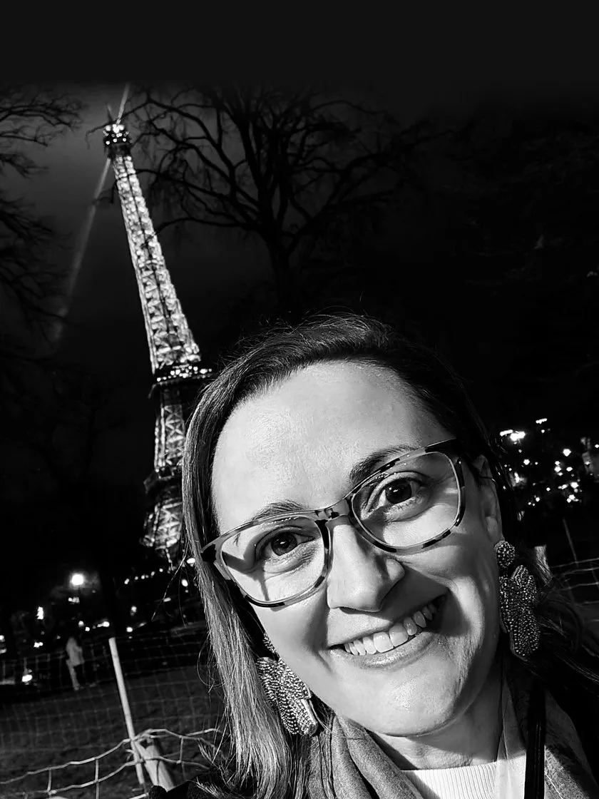 Gayle smiling in front of the Eiffel Tower at night, in black and white